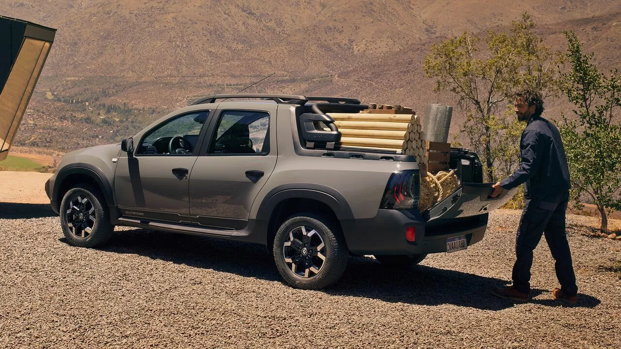 Visual externo do Renault Oroch, enquanto homem coloca itens na caçamba da picape média