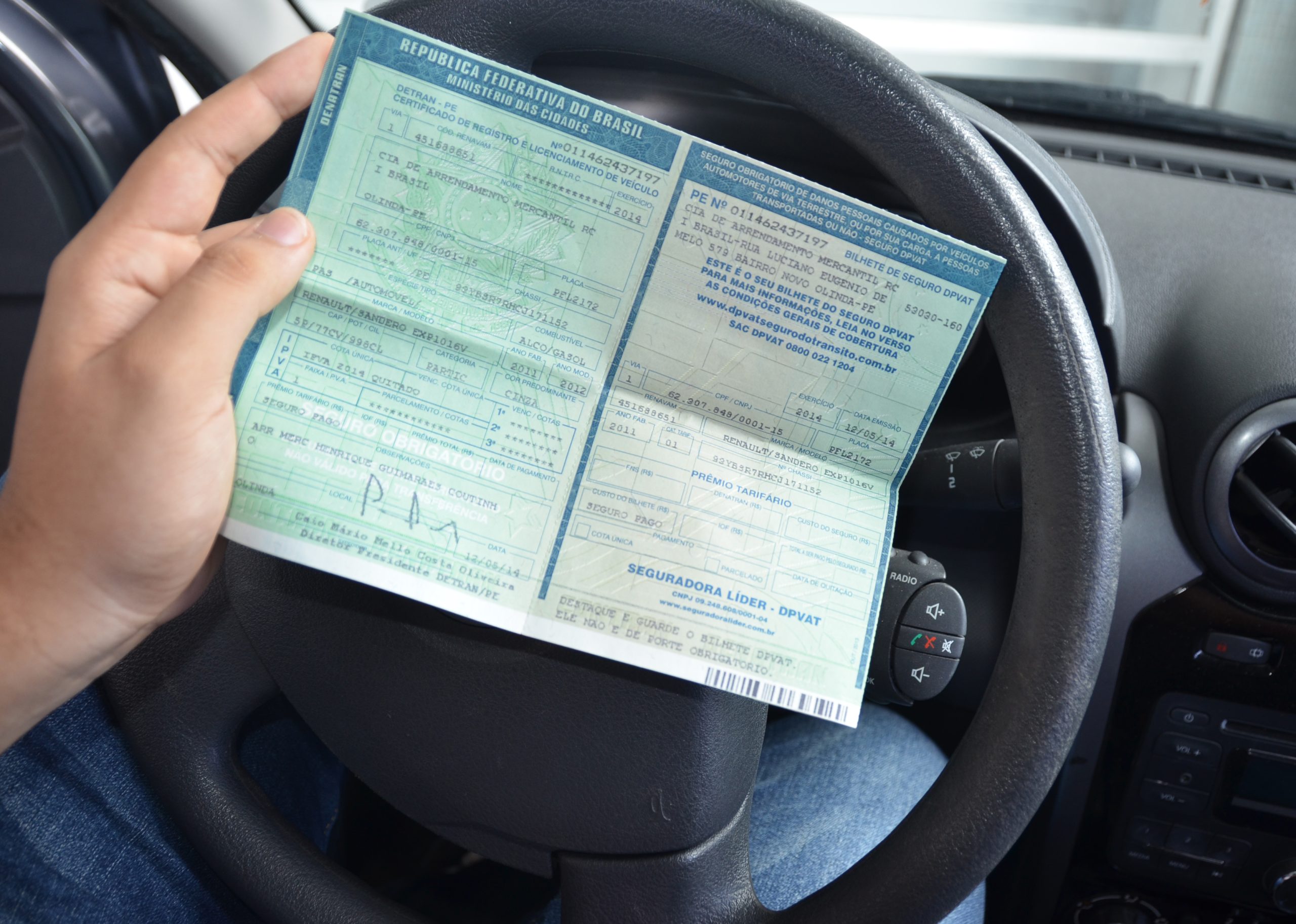 Pessoa segurando o documento de licenciamento veicular