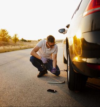 Jovem consertando carro quebrado na estrada