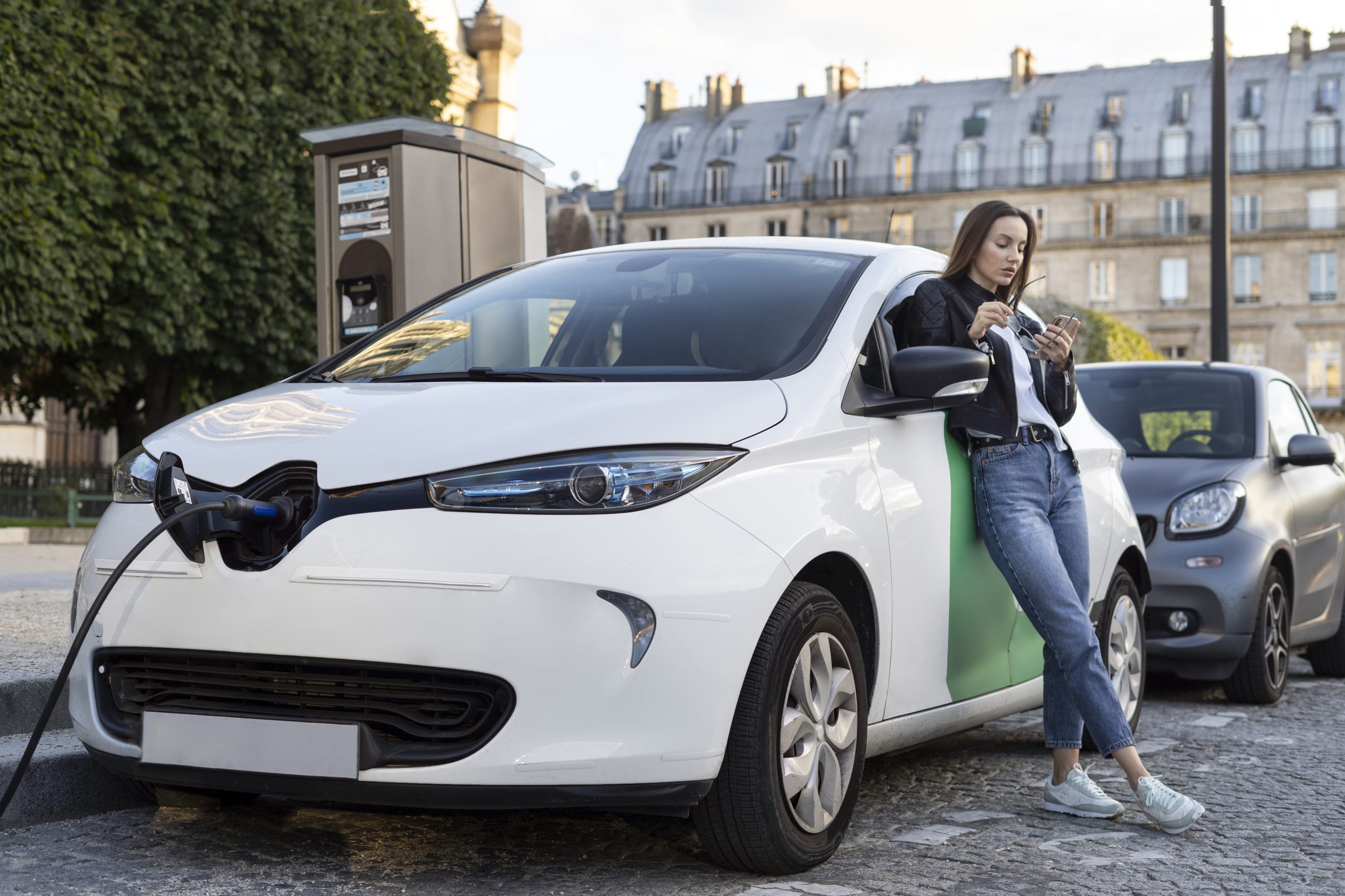 Mulher encostada em um carro elétrico carregando