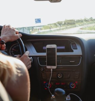 Mulher dirigindo um carro com o celular no painel