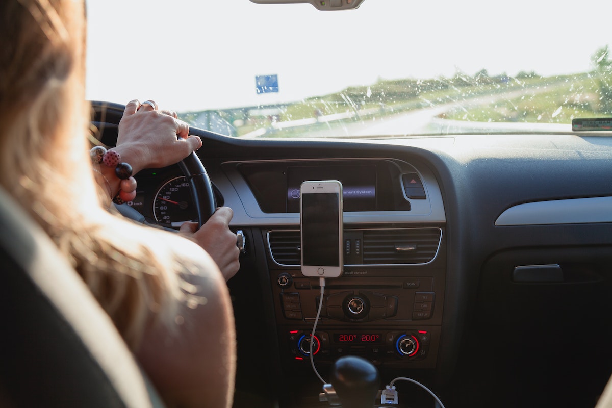 Mulher dirigindo um carro com o celular no painel