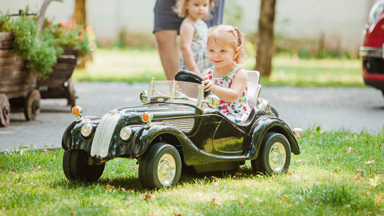 Menina dirigindo carro para criança no gramado