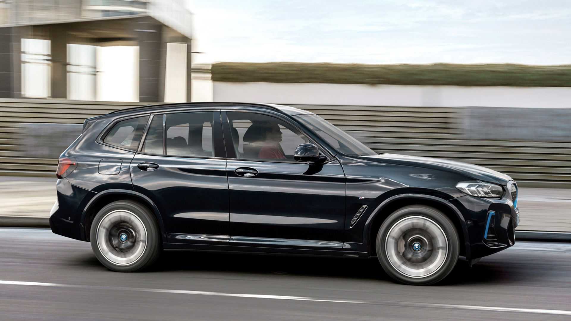 Visão lateral de um homem conduzindo o BMW iX3 2024 na cor preta