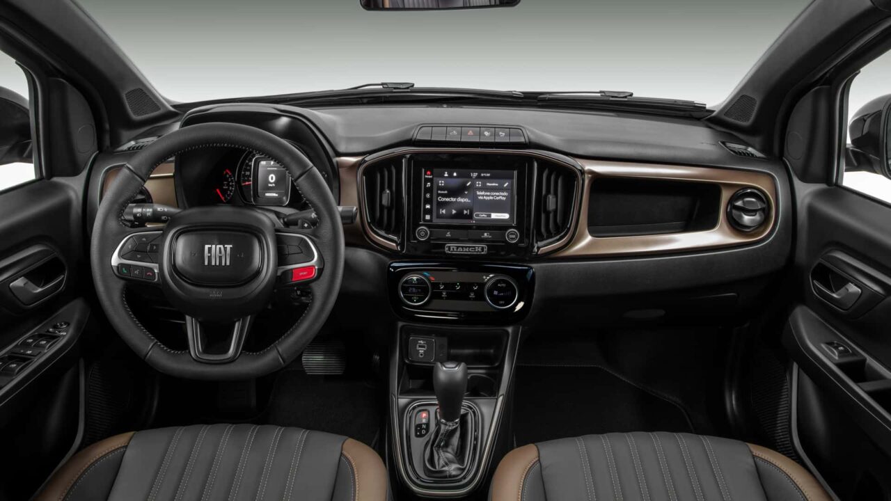 Volante, painel e detalhes do interior, na cor preta, da Fiat Strada Sporting 2024 