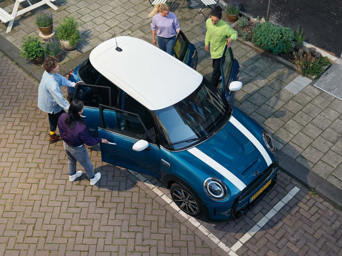 VIsão do teto do MINI Cooper S 2024, na cor azul, com pessoas abrindo cada uma das portas do veículo