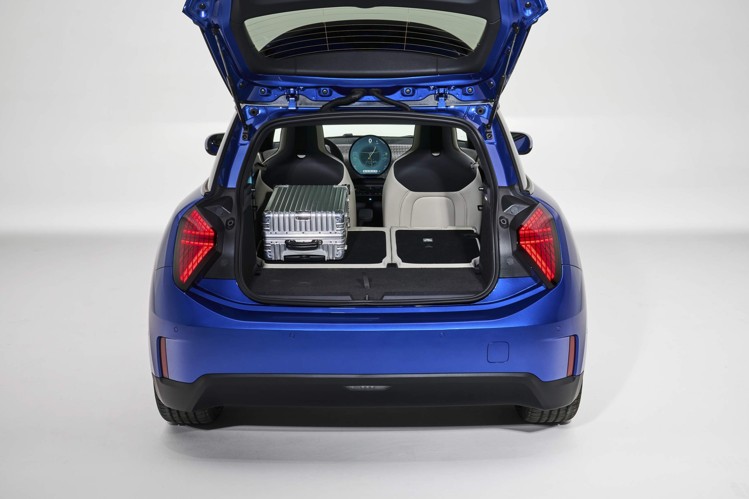 Tampa do porta-malas do Mini Cooper SE 2024, na cor azul, aberta, mostrando malas no interior