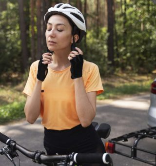 Mulher colocando capacete enquanto monta em bicicleta que acabou de tirar do carro