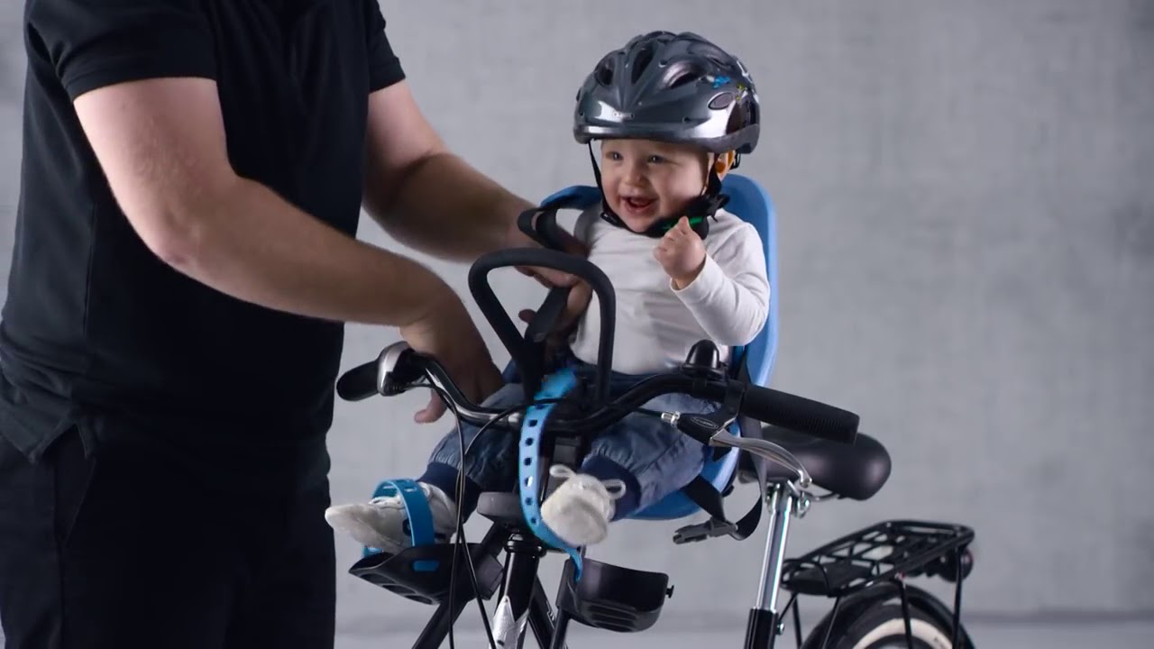 Pai colocando a criança em uma cadeirinha de bicicleta dianteira