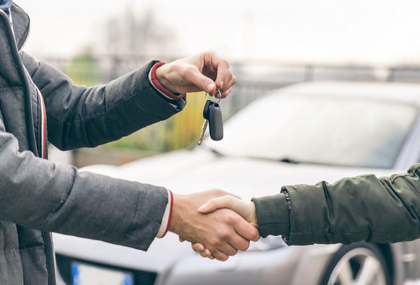Duas pessoas apertando as mãos após fechar a compra de um carro
