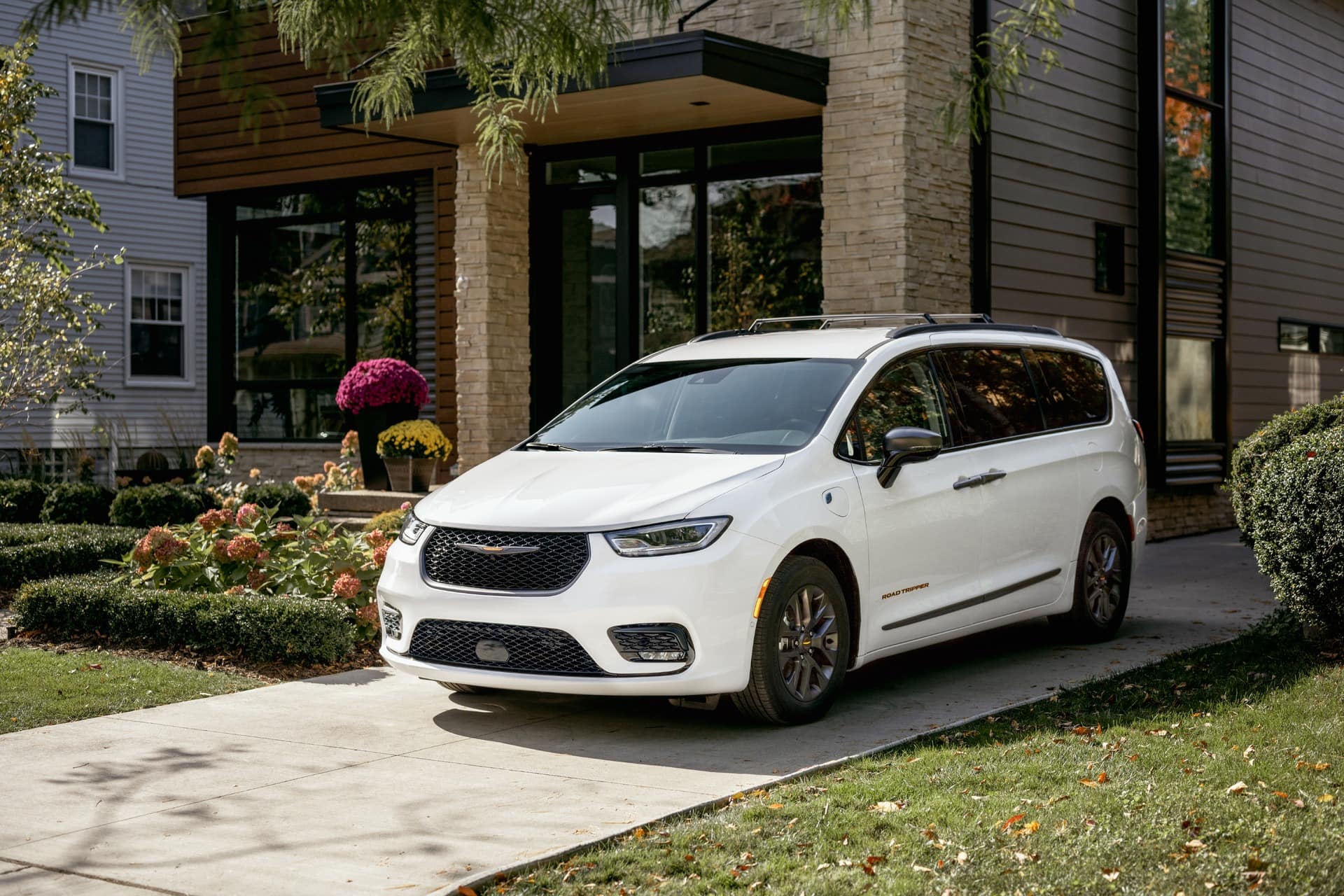 Minivan Chrysler Pacifica 2024 branca, estacionada na frente de uma casa